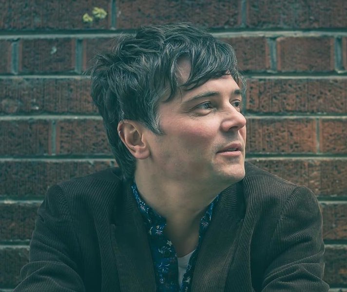 side view photograph of man (Andrew) with a brick background